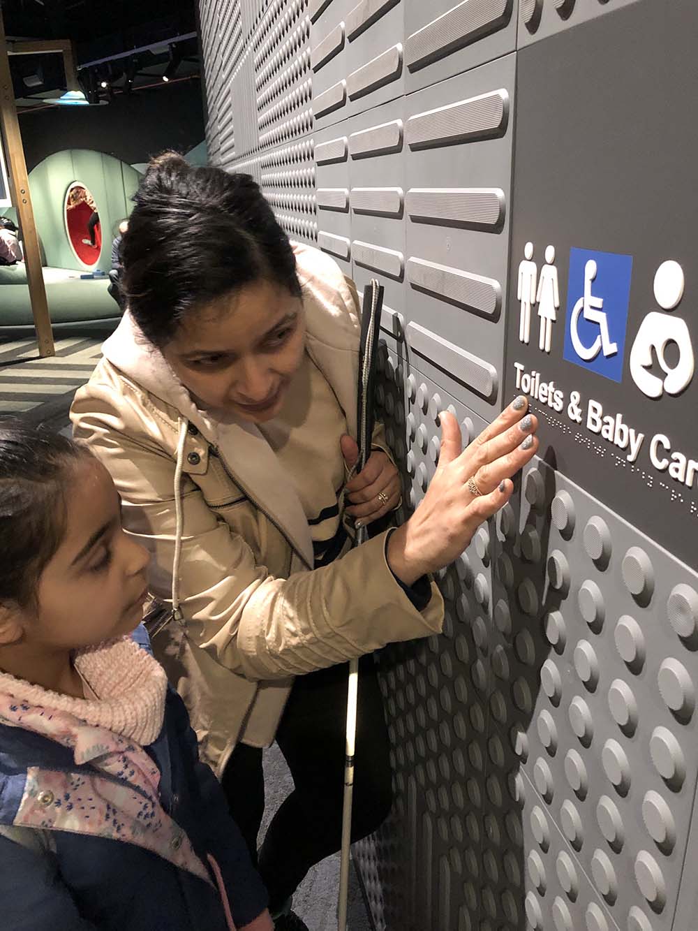 Mother demonstrates braille signage to child.